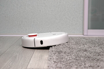 Robot vacuum cleaner drives on carpet. Overcoming obstacles with robot vacuum cleaner. ideal cleaning of house with modern wireless appliances. concept of smart home.