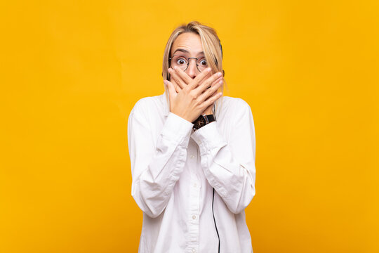 young woman telemarketer covering mouth with hands with a shocked, surprised expression, keeping a secret or saying oops