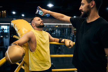 Satisfied trainer pouring water on his tired champion