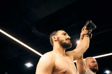 Bearded boxer getting his arm raised by referee