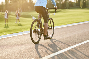 Cropped shot of a man riding mountain bike in park during sunset, cycling outdoors on a summer day