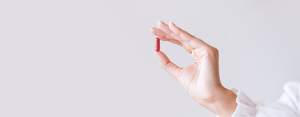 Woman in white blouse holding in hand iron Ferrum supplement capsule. Bioactive additive woman...