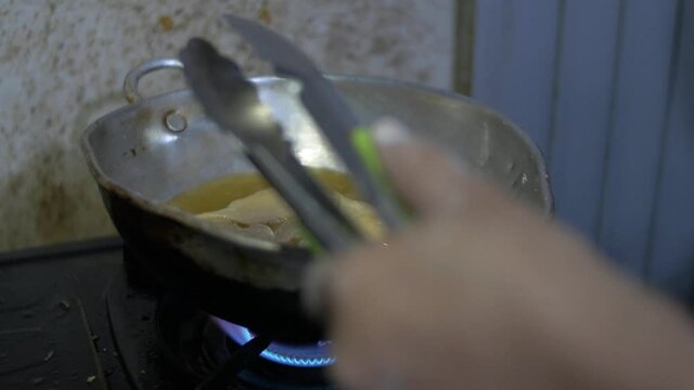 Deep frying cooking process of pangsit goreng or fried dumpling in hot oil