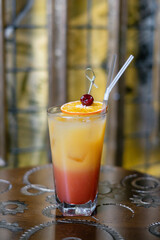 Cocktail with ice and orange liqueur in a tall glass, decorated with cherry and orange.