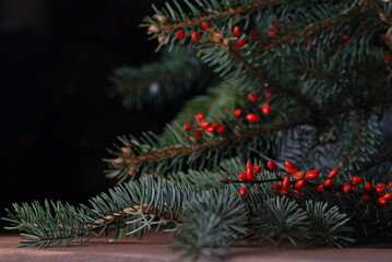 Christmas tree branches with red berries and blurred lights