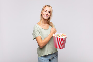 young woman with a pop corns bucket feeling happy, positive and successful, motivated when facing a challenge or celebrating good results