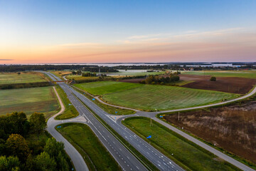 Fototapeta na wymiar Aerial view of a highway passing through agricultural fields at sunrise