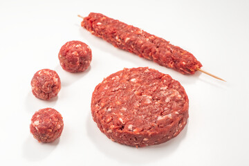 Close-up on raw meatballs, patty and kebab on white background