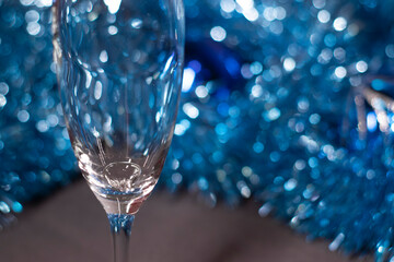 an engagement ring in a champagne glass near blue shiny tinsel for christmas tree. new years...
