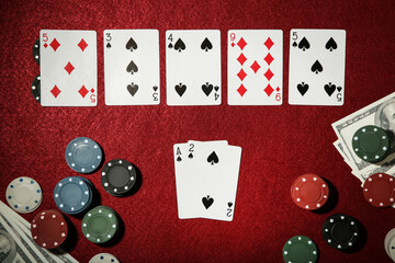 Cards with poker chips and dollar banknotes on red table