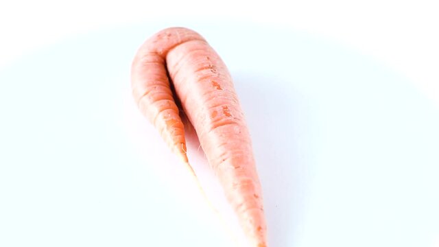 Ugly carrot rotate on a white background. Funny, unnormal vegetable or food waste concept. Horizontal orientation