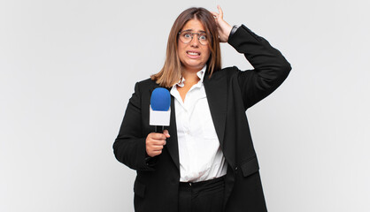 young woman reporter feeling stressed, worried, anxious or scared, with hands on head, panicking at...