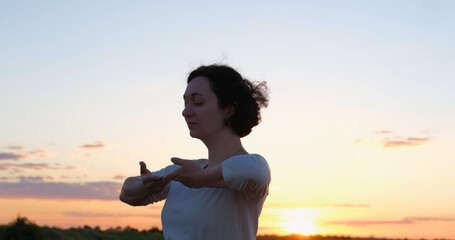 Female practicing qigong in summer fields with beautiful sunset on background	 - 381998731