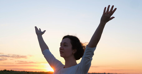 Female practicing qigong in summer fields with beautiful sunset on background	 - obrazy, fototapety, plakaty