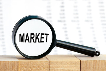 Look closely and MARKET with a magnifying glass , business concept image with soft focus background