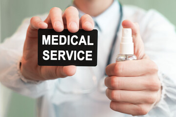 Doctor holding a paper card with text MEDICAL SERVICE and the medicine bottle, medical concept