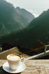 Hot latte coffee in winter morning at hillside with mountain background. Copy space for text.
