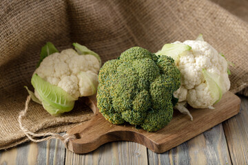 Fresh broccoli and cauliflower on rustic wooden table with jute sack