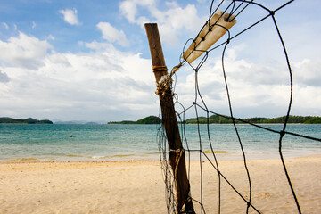 Beach volleyball net on the empty beach with the blue sea and sky. Copy space.
