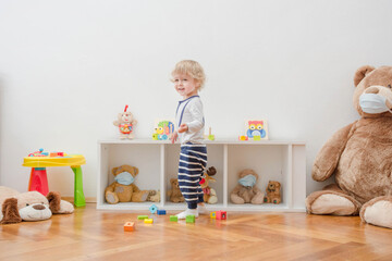 Child in home quarantine having fun playing with colorful wooden blocks, at home