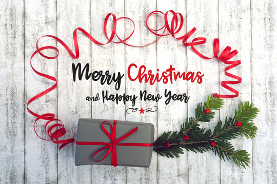 Weihnachtshintergrund, grüner Zweig, Text Frohe Weihnachten, Geschenk und Geschenkband mit Schwung rot, weißes Holz, Beeren, Früchte.