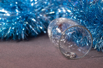 an engagement ring in a champagne glass near blue shiny tinsel for christmas tree. new years proposal theme.