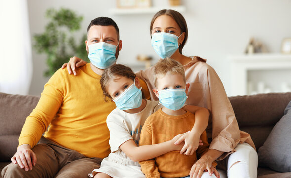 Family In Protective Medical Masks In The Midst Of The Coronavirus Pandemic At Home.