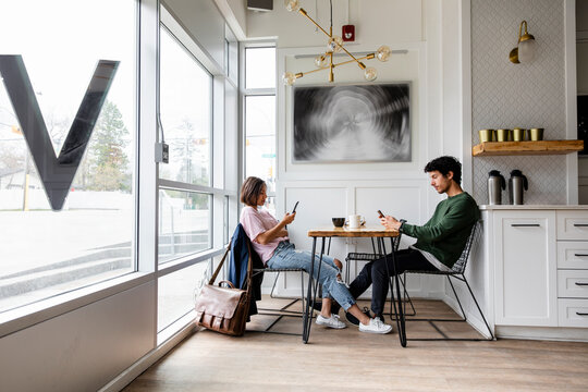 Young couple using smart phones and drinking coffee at cafe table