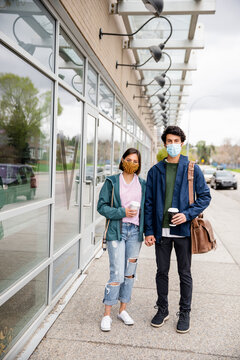 Portrait confident young couple in face masks with coffee outside cafe