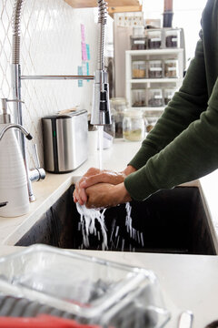 Male barista washing hands at cafe sink