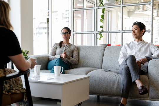 Coworkers Meeting On Breakout Sofa In Coworking Space