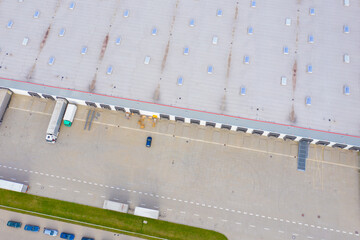 Aerial Shot of Industrial Warehouse Loading Dock where Many Truck with Semi Trailers Load Merchandise.