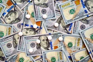USA national currency, top view of mixed American dollars banknotes with white pills on it, drugs,...