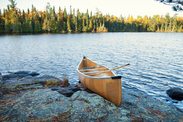 Yellow canoe on rocky shore of northern Minnesota lake at sunrise during autumn