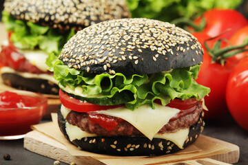 A black burger with vegetables and beef meat