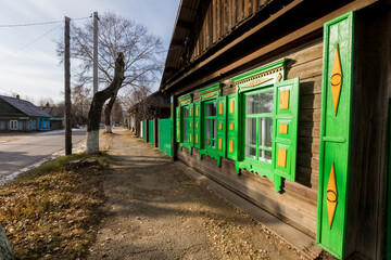 An old one-story wooden house with carved shutters in the Russian style. Wooden house on the street of a Russian town