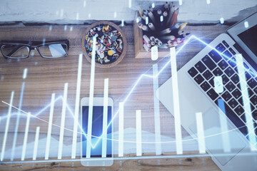 Double exposure of financial graph hologram over desktop with phone. Top view. Mobile trade platform concept.