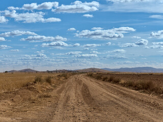 Fototapeta na wymiar Country side view with empty road, blue sky and white cotton clouds