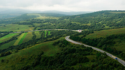 Fototapeta na wymiar Aerial view over mountain road going through forest landscape