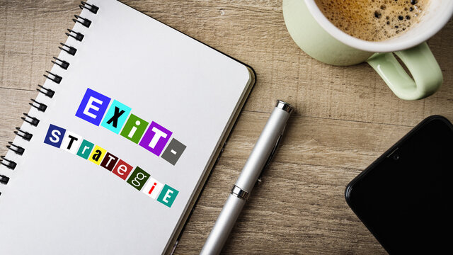 Exit-Strategie.. Flat Lay. Arbeitsbereich mit Notizblock, Kugelschreiber, Handy und einer Tasse Kaffee.