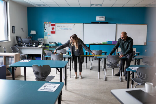 Teachers measuring social distance in class