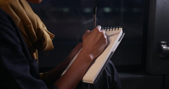 Close-up african-american woman writing with pen on notebook on bus