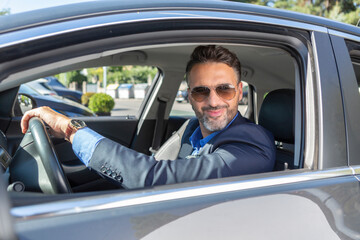 Confident handsome businessman smiling in the car