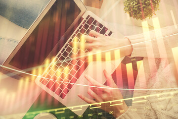 Double exposure of woman hands working on computer and forex chart hologram drawing. Top View. Financial analysis concept.