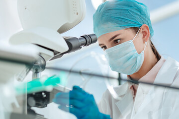 close up. female researcher looking through a microscope.