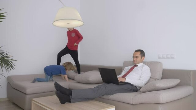 Relaxed Business man working on laptop at home, children jump on the couch, isolation, successful free lancer