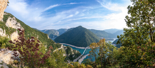 Massive panorama of Lake Piva or Pivsko jezero in Montenegro. View to the bridge from Durmitor to Pluzine town. Unbelievable serpentine road with tunnels. Lovely blue sky with clouds.