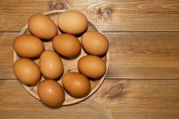 Brown fresh chicken eggs in  wooden plate on wood backdgound. Organic rural products concept.