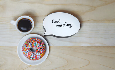 Cup of coffee with a donut and a plate on a wood texture background. Concept on the topic Good Morning
