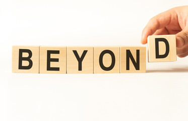 Word beyond. Wooden small cubes with letters isolated on white background with copy space available. Business Concept image.